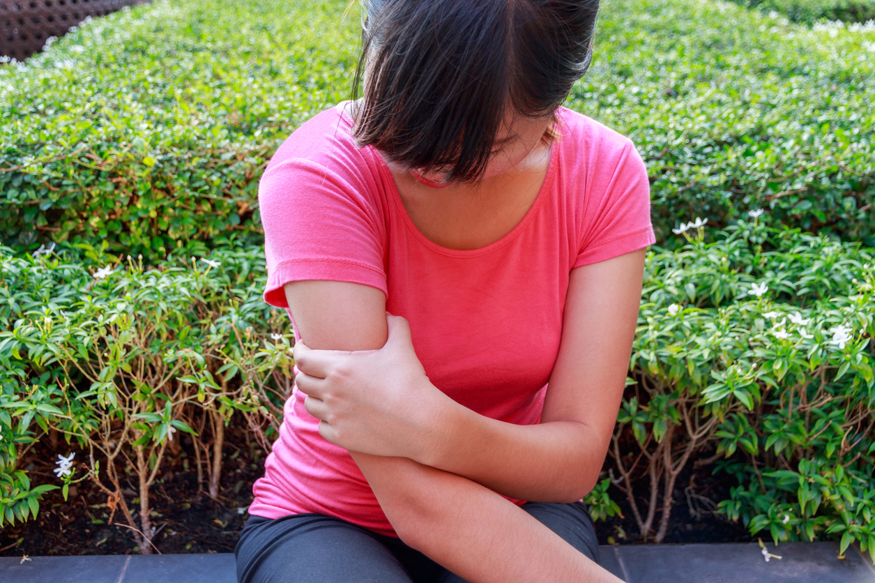 Female arm pain sitting in the park